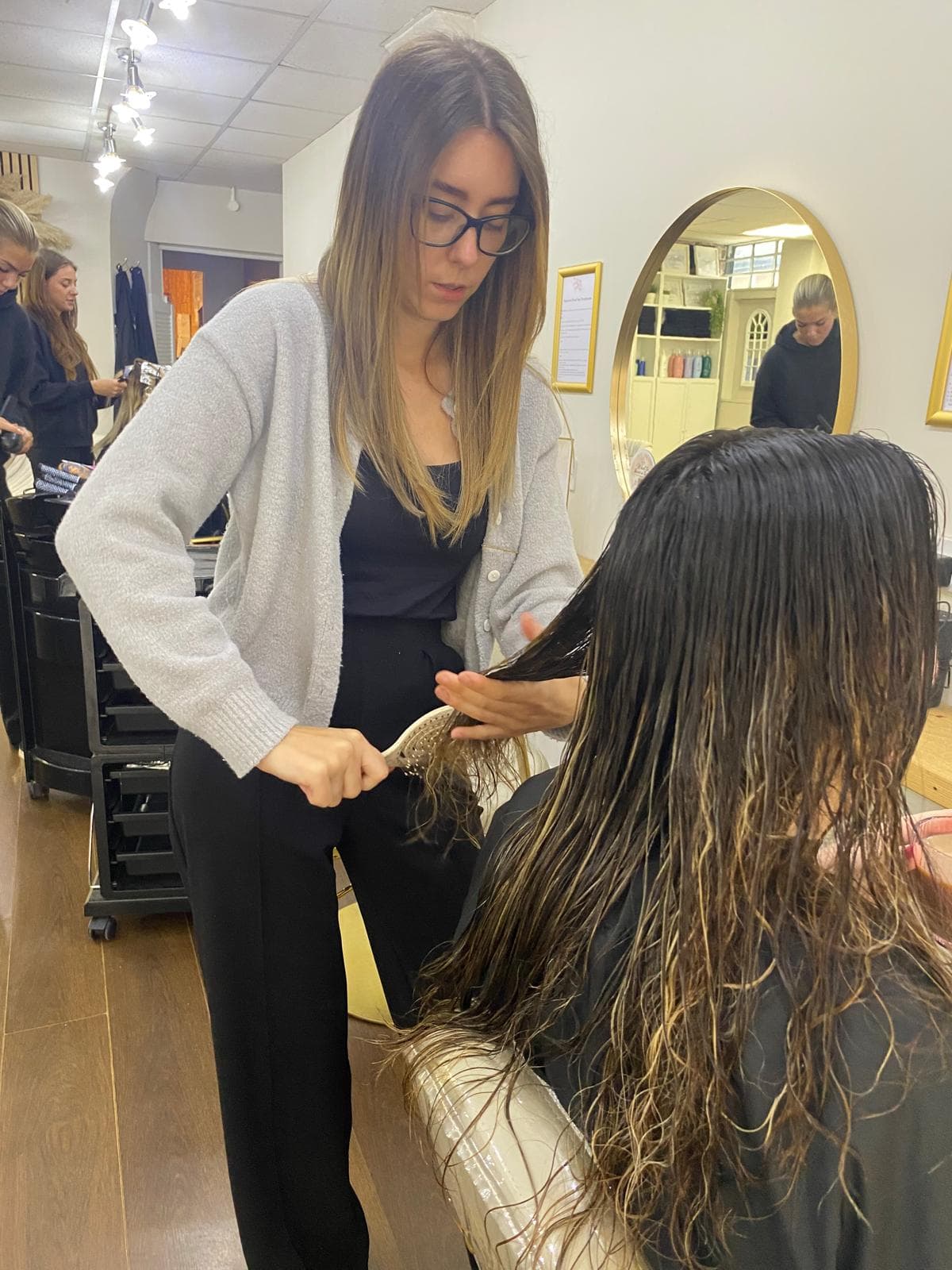 Chloe Collins, Senior Designer at The Vintage Avenue, brushing through wet hair before styling a client in the salon.