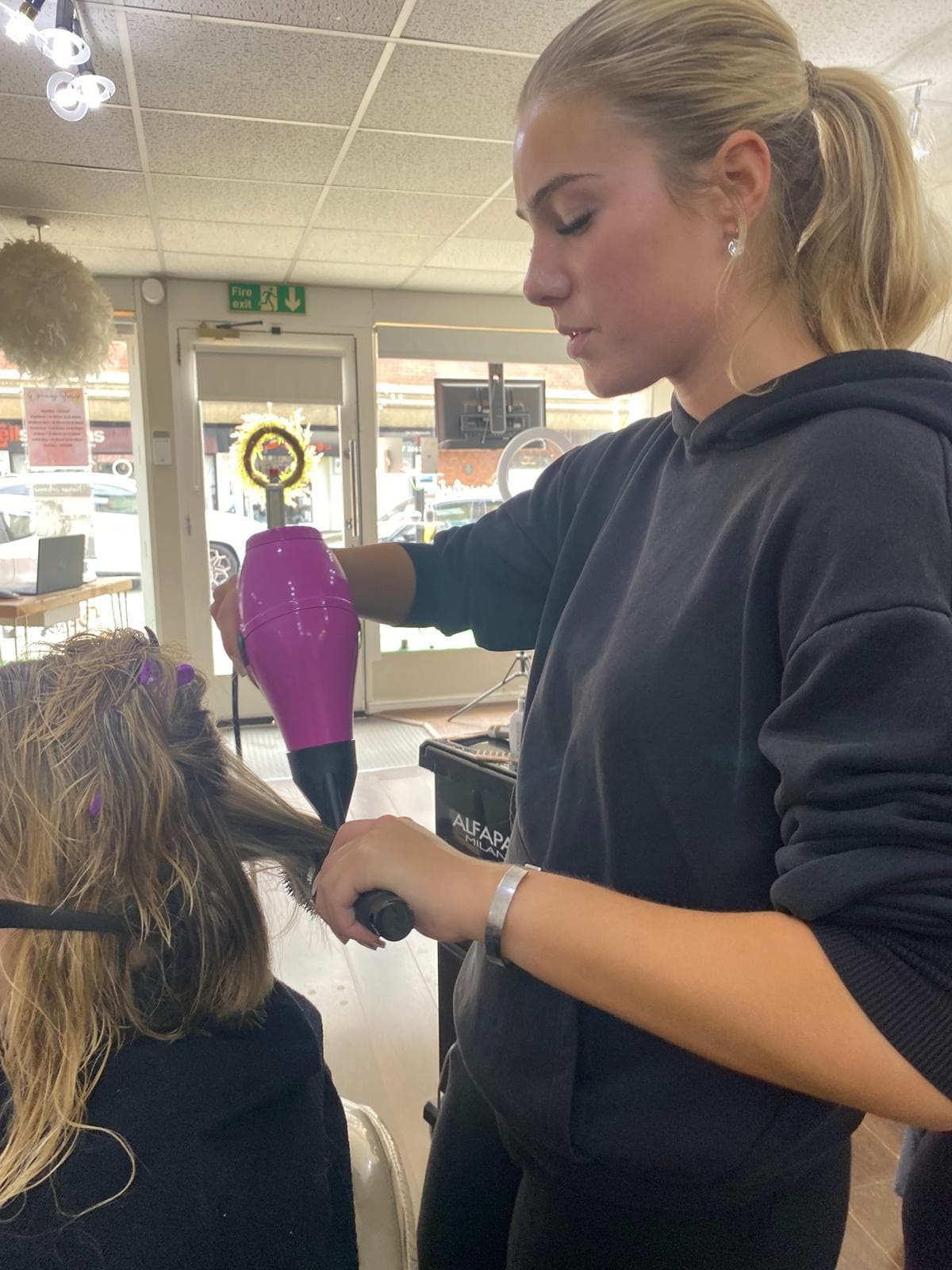 Eliza Fuller, Co-Stylist at The Vintage Avenue, blow-drying a client’s hair with focus and care in the salon.