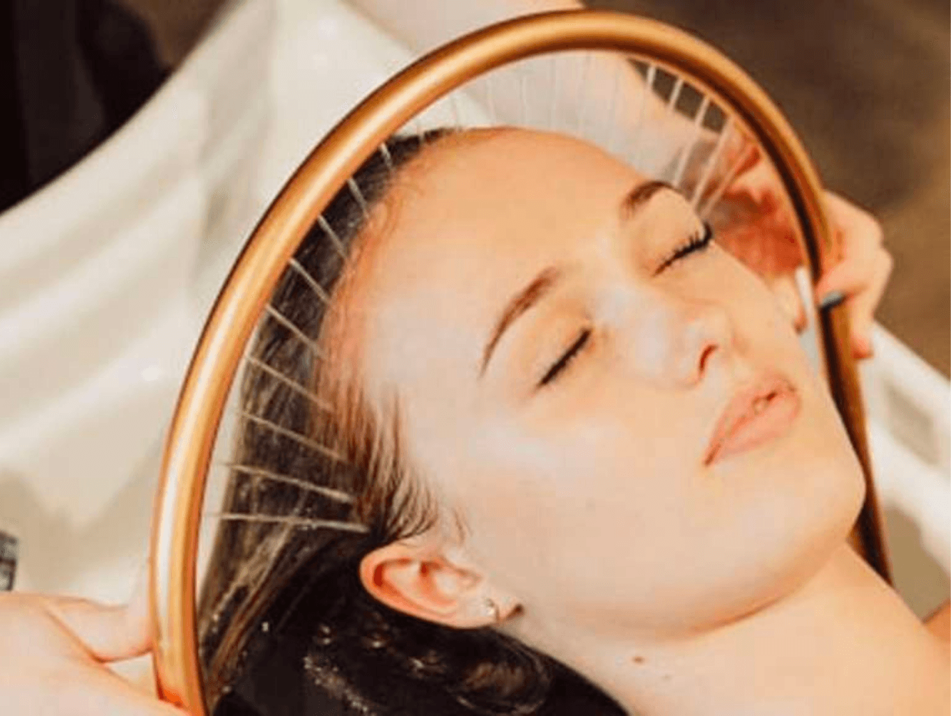 Woman receiving a relaxing Japanese head spa treatment with a warm towel wrap at The Vintage Avenue Skin Clinic.