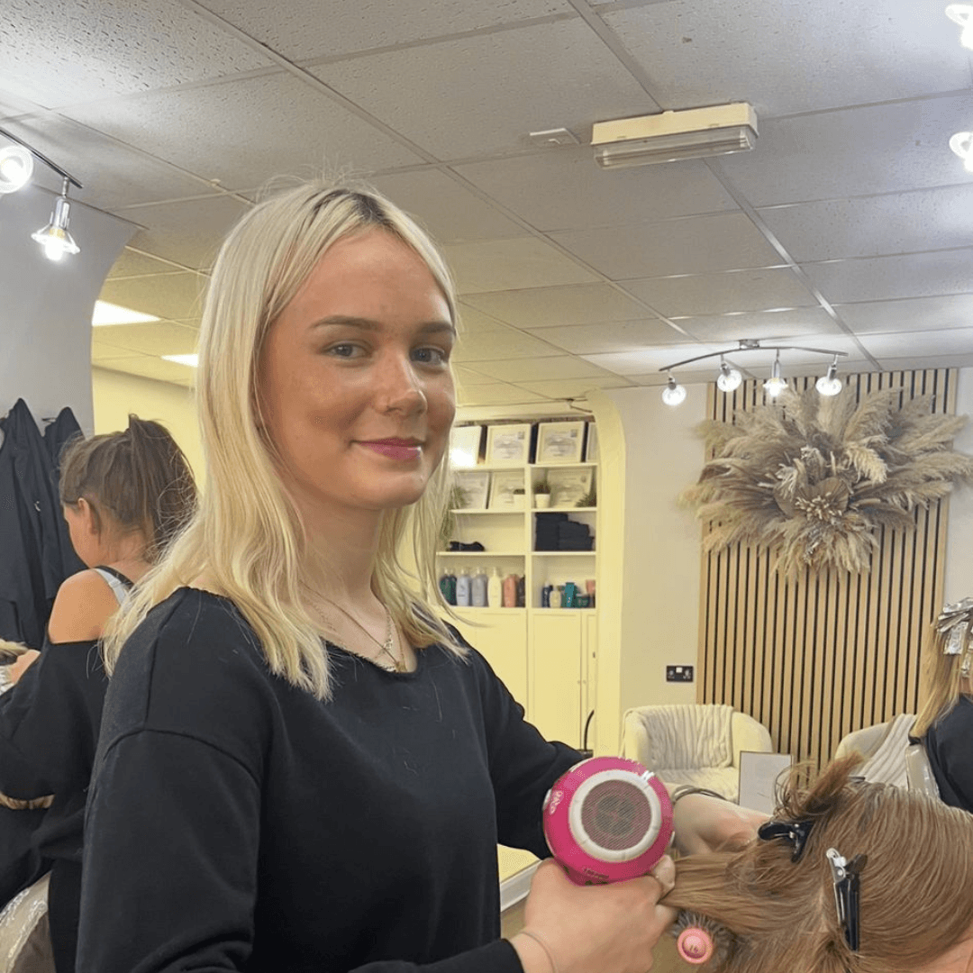 Mia, graduate stylist at Vintage Avenue, blow-drying a client’s hair in the salon